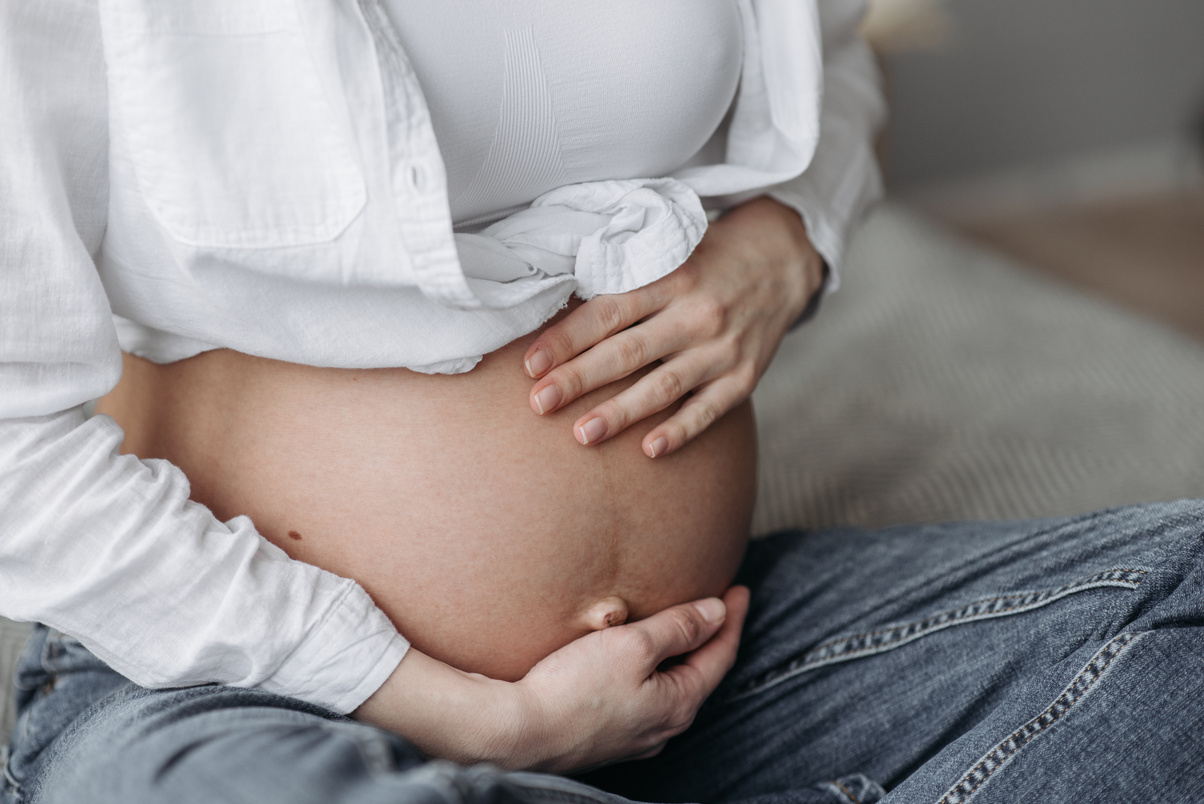 Pregnant Woman in White Top and Blue Denim Jeans